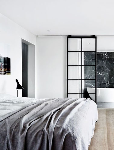 Cette chambre parentale moderne accueille une porte coulissante en verre au style d'une verrière intérieure réalisée par un ferronnier et montée sur rail, top la déco !