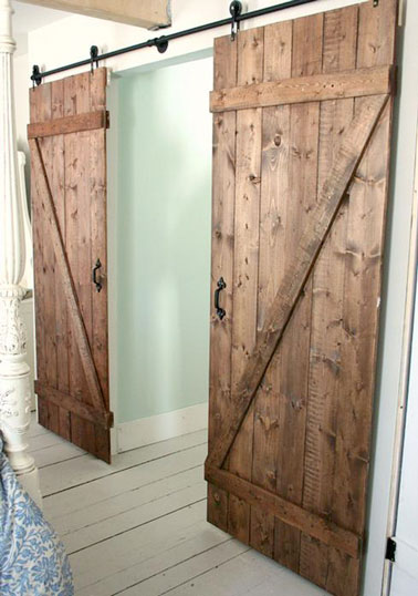 Pour gagner de l'espace et en alternative à une porte classique, cette double porte coulissante en bois montée sur rail et à fabriquer soi-même donne du charme à la chambre 