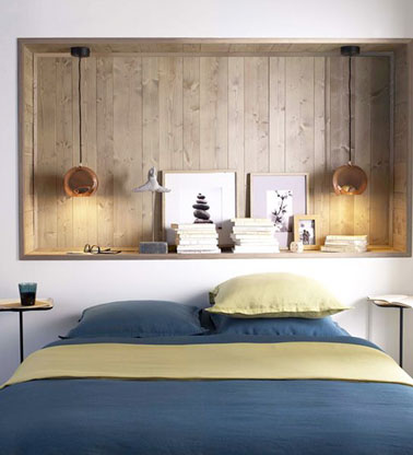 La tête de lit se fait pratique dans cette petite chambre à la déco symétrique et offre une niche de rangement dans le mur permettant de gagner de l'espace 