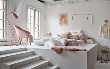 Un petit coin douillet spécialement aménagé pour la nuit prend place sur l'estrade et maximise l'espace de cette jolie chambre blanche aux touches rose pastel 