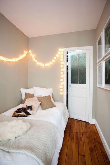 Toute en longueur, cette petite chambre coquette illuminée d'une guirlande invite à la détente dans son lit agencé contre le mur faisant office de cocon douillet