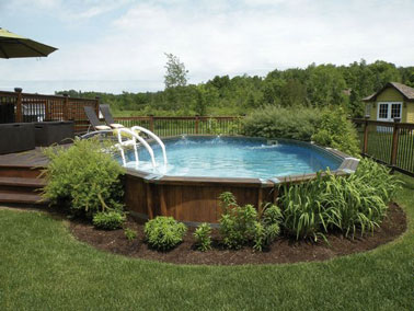 Voilà un magnifique cadre pour se reposer sur cette terrasse en bois entourée de pelouse et aménagée avec une piscine hors sol où la végétation s'est invitée. 