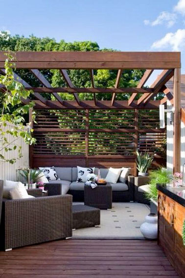Confort absolu sur cette petite terrasse aménagée avec une pergola et un brise-vue en bois permettant de faire la sieste tranquillement sur le canapé de jardin