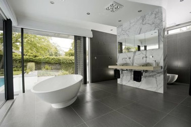 Avec un carrelage gris anthracite et un délimiteur aspect marbre, cette salle de bain a tout de design ! Une déco soulignée par une baignoire îlot, c'est top !