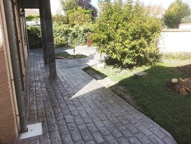 Verdure et béton imprimé à motif en briques s'accordent parfaitement dans la déco extérieure derrière la maison ! Un sol qui apporte de la valeur ajoutée au jardin !