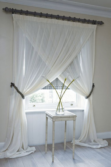 Voilà une idée qui sort de l'ordinaire ! Dans cette chambre blanche, les rideaux blancs ont été croisés afin de donner de l'originalité à la pièce et laisser entrer la lumière 