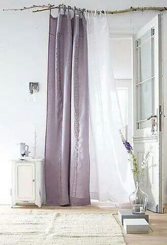 Les rideaux blancs et parme de cette chambre adoptent la déco récup et remplace la tringle par une branche de bois flotté qui offre un effet déco unique et original ! 