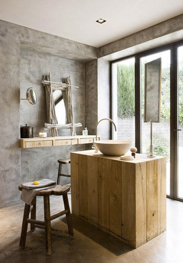 Béton ciré sur les murs et le sol combiné à des touches de bois données par un îlot central et des tabouret, voilà une salle de bain ultra déco et originale !