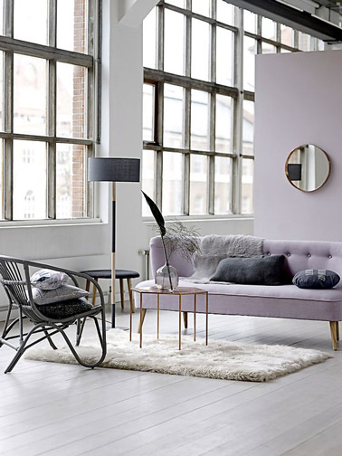 Voilà un salon couleur pastel plein de douceur ! Couleur parme, parquet blanc, tapis, et mobilier tendance assure une déco cosy soulignée par un fauteuil en rotin noir