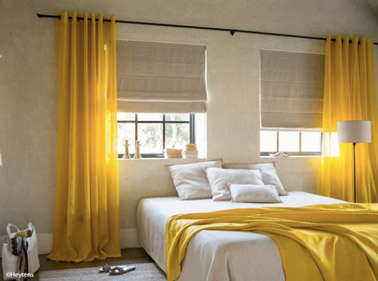 Dans cette chambre beige, la déco est dynamisée grâce aux rideaux jaunes qui donnent du peps à la pièce et font un clin d'oeil au plaid de la même couleur ! 
