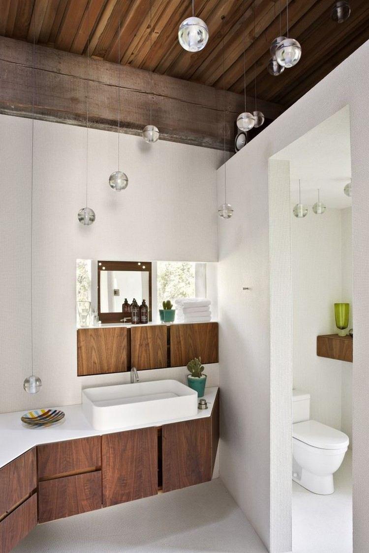 On craque pour cette charmante salle de bain blanche et bois et ses jolis luminaires ! Une ambiances douce soulignée par des suspensions transparentes rondes