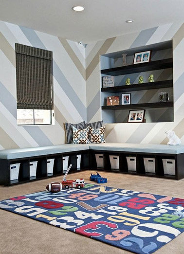 Pour tout ranger facilement, cette salle de jeux dispose d'une niche en hauteur et d'une banquette sous laquelle une multitude de compartiments avec des paniers peuvent accueillir les jouets 