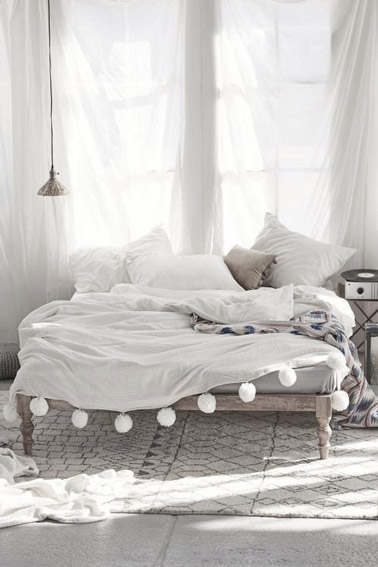 On craque pour le style bohème de cette chambre aux tons naturels où la déco est joliment soulignée par des voilages blancs, un lit en bois et un beau tapis 