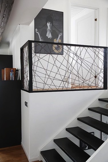 Juste à côté des escaliers, un garde corps en fer noir hyper design trouve parfaitement sa place dans cette déco intérieure moderne dominée par le blanc et le noir 