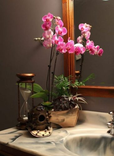 L'orchidée apporte une décoration délicate et harmonieuse sur un rebord de lavabo.