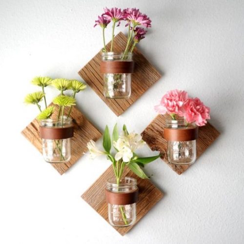 Pots de confiture utilisés comme pots de fleurs sur leurs supports muraux