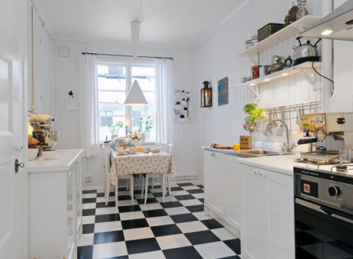 Une cuisine toute blanche en contraste avec un sol à damier