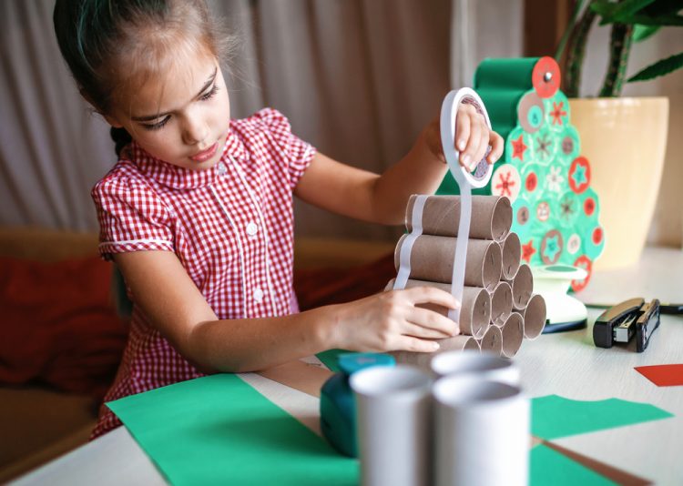 Une petite fille qui fait un calendrier de l’Avent maison avec des rouleaux de papier toilettes