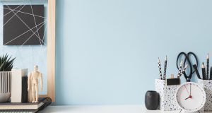 bureau blanc et un mur bleu ciel, avec des pots à crayons et une petite plante