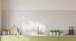 Cuisine avec des murs blancs et un plan de travail vert. Sur le mur il y a une crédence blanche.