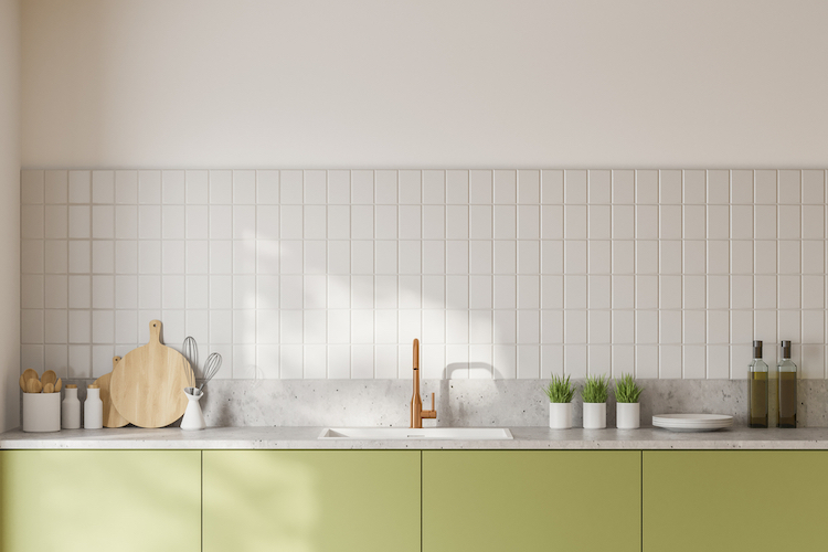 Cuisine avec des murs blancs et un plan de travail vert. Sur le mur il y a une crédence blanche.