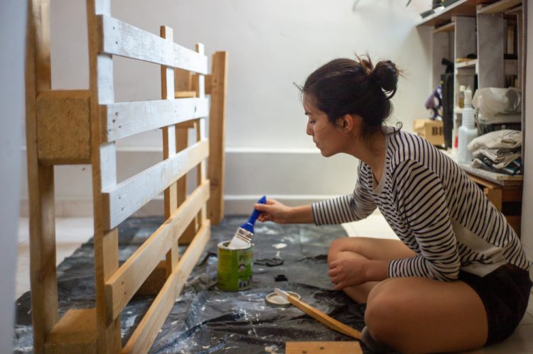 jeune femme qui applique une lasure pour protéger ses meubles en palette